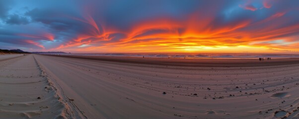 panoramic view of a wide beach during sunset with distant figures walking along the shoreline