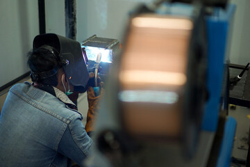 Welder performing Tungsten Inert Gas welding process (TIG) on stainless steel. TIG welding uses the heat generated by an electric arc struck between a non-consumable tungsten electrode and the work
