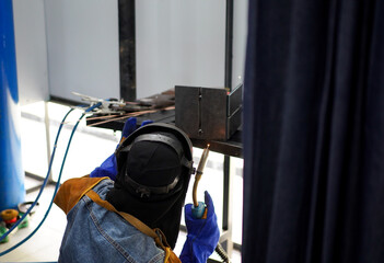 Welder performing Tungsten Inert Gas welding process (TIG) on stainless steel. TIG welding uses the heat generated by an electric arc struck between a non-consumable tungsten electrode and the work