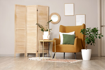 Interior of light living room with mirror, armchair and folding screen