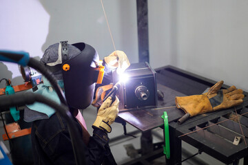 Welder performing Tungsten Inert Gas welding process (TIG) on stainless steel. TIG welding uses the heat generated by an electric arc struck between a non-consumable tungsten electrode and the work
