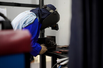 Welder performing Tungsten Inert Gas welding process (TIG) on stainless steel. TIG welding uses the heat generated by an electric arc struck between a non-consumable tungsten electrode and the work