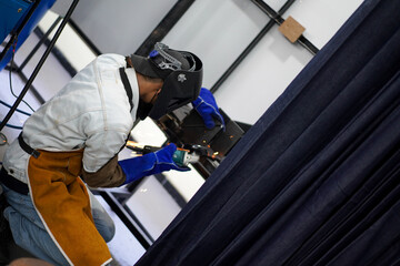 Welder performing Tungsten Inert Gas welding process (TIG) on stainless steel. TIG welding uses the heat generated by an electric arc struck between a non-consumable tungsten electrode and the work