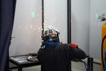Welder performing Tungsten Inert Gas welding process (TIG) on stainless steel. TIG welding uses the heat generated by an electric arc struck between a non-consumable tungsten electrode and the work