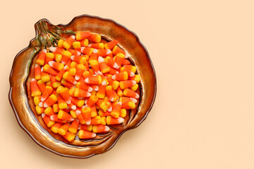 Plate with tasty Halloween candy corns on color background
