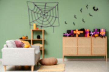 Interior of stylish living room decorated for Halloween with sofa, shelving unit and chest of...