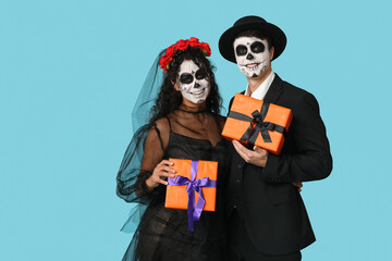 Young couple dressed for Halloween with gift boxes on blue background