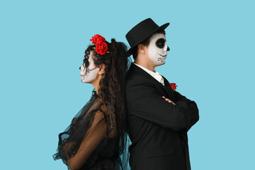 Young couple dressed for Halloween on blue background