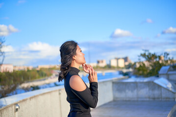 A woman is standing on a balcony and pointing to the sky. She is wearing a black dress
