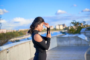A woman is standing on a balcony and pointing to the sky. She is wearing a black dress