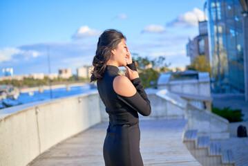 A woman is standing on a balcony and pointing to the sky. She is wearing a black dress
