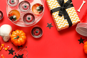 Composition with sweet jelly dessert, gift box and decorations for Halloween party on red background