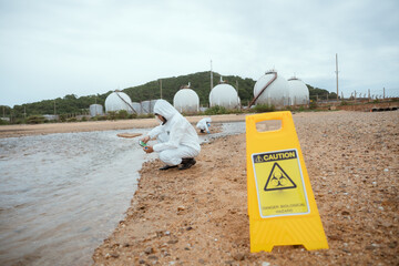 Obraz premium Close up of Warning Biohazard sign at ecological disaster site with people in protective suits, copy space