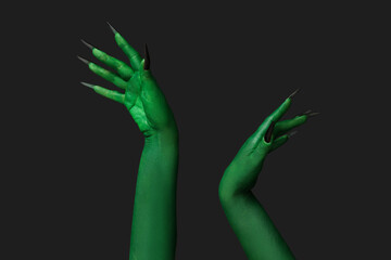 Green hands of witch on black background. Halloween celebration