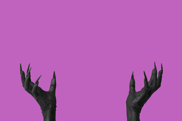 Black hands of witch on purple background. Halloween celebration