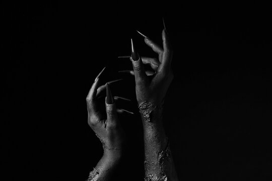 Black hands of witch on dark background. Halloween celebration
