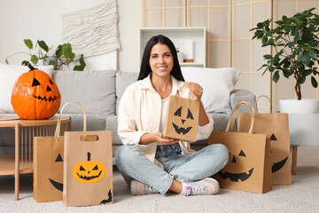 Young woman with shopping bags for Halloween sitting on floor at home
