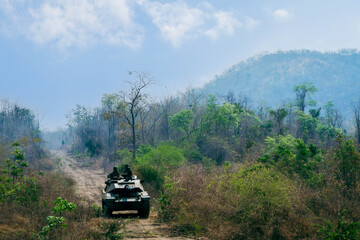Armored on Patrol, A armored vehicles carrying armed soldiers advances along a dirt path during a...