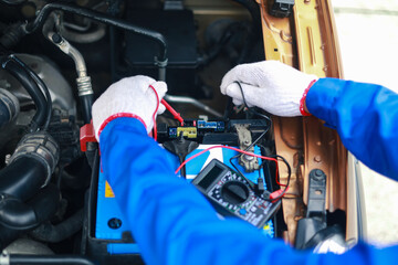 Auto mechanics check car engines with digital multimeters, test batteries and fuse boxes, and...