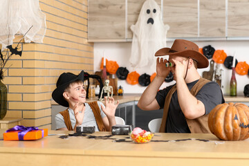 Scary father with his son dressed for Halloween as cowboys in kitchen