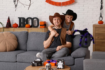 Father with his son dressed for Halloween as cowboys hugging at home