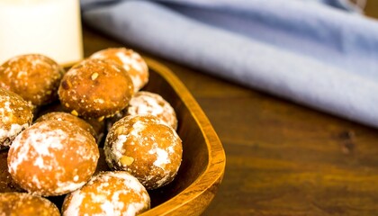Homemade donut holes dusted with powdered sugar in a wooden bowl