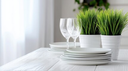 Glasses, plates, and green houseplant placed neatly on white wooden table, home vibe