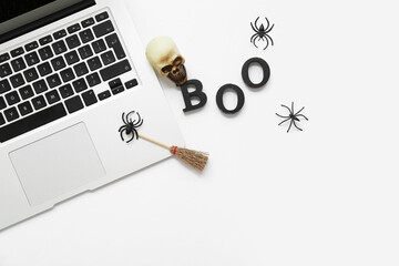 Modern laptop with Halloween decorations and word BOO on white background