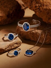 Warmly Lit Photograph – Elegant Collection of Silver and Blue Jewelry on Soft Textured Background
