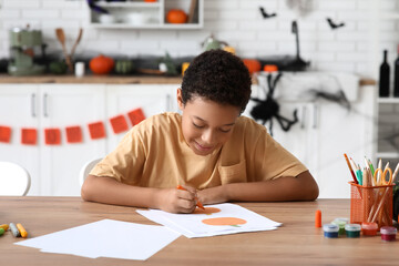 Naklejka premium Teenage African-American boy drawing Halloween picture at home