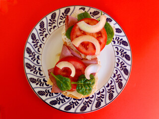 Pastrami on a bun with cheese, tomato and onion.