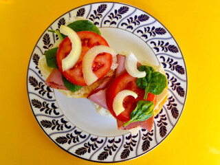 Pastrami on a bun with cheese, tomato and onion.