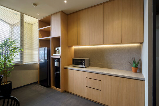 Modern office pantry with wooden cabinets, microwave, and water dispenser. A minimalist and functional kitchen area for a contemporary workspace. - Powered by Adobe
