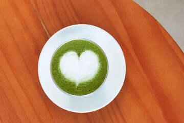 A cup of green tea matcha latte on wooden background                                                                                                                                                    