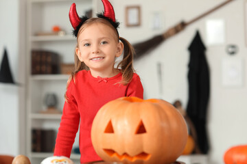 Cute little girl in devil horns dressed for Halloween at home