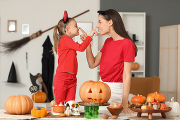 Happy mother and her little daughter dressed for Halloween touching each other's noses at home