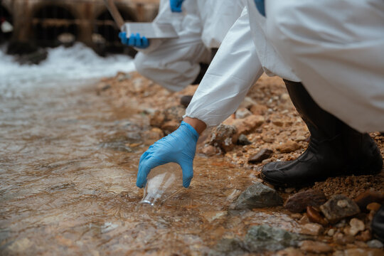 Scientist collects water sample from river for environmental testing during daytime