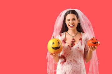 Young woman dressed for Halloween as dead bride with pumpkins on red background