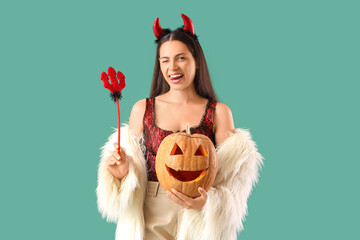 Young woman with Halloween pumpkin on green background