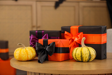 Coffee table with pumpkins and Halloween gift boxes in living room, closeup