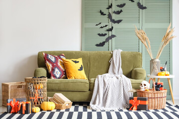 Interior of festive living room with green sofa, Halloween decorations and gift boxes