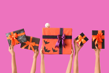 Female hands with Halloween gifts and skull on purple background