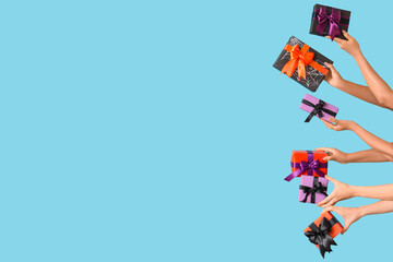 Female hands with Halloween gifts on blue background