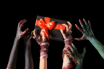 Painted female hands with Halloween gift on black background