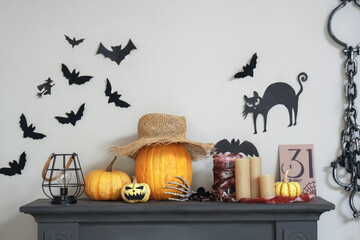 Fireplace with Halloween decorations near white wall with paper bats, cat and fetters