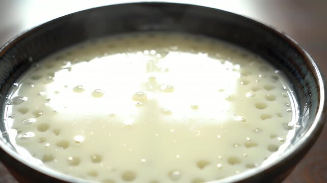 Macro Video of Creamy Tapioca Pudding in Ceramic Bowl on Wooden Table Top Showcasing Smooth Texture Translucent Pearls and Delicious Creaminess Perfect for Food Promotion and Dessert Recipe Video in