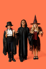 Cute happy children in different costumes dressed for Halloween party on orange background