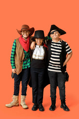 Cute happy boys in different costumes dressed for Halloween party on orange background