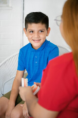 Dentist teaching oral hygiene to smiling young boy using dental mold