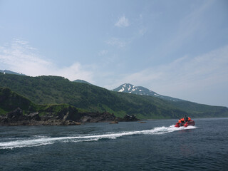 Boat tour on Kuril Islands along the Iturup coast with Volcano in background